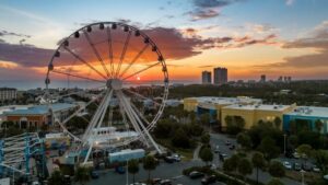 Aerial shot of a ferris wheel at sunset a beach side town